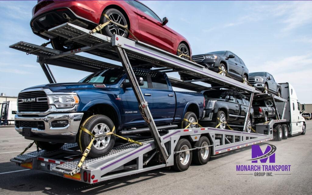 Monarch Auto Transport Broker vs. Carrier Which One Should You Use (8) A large multi-car transport trailer loaded with modern American SUVs and pickup trucks in a bright, professional environment.