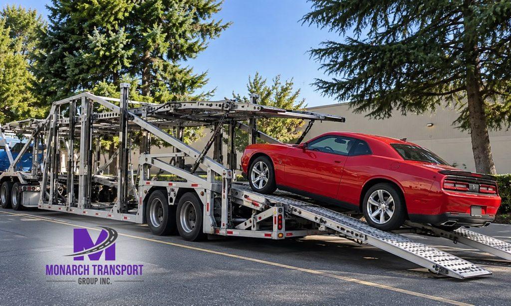 Monarch - How Car Carrier Trucks Work- Single-Car vs Multi-Car Transport Explained 3 Open car carrier trailer loading a sedan onto the lower deck via metal loading ramps, with the upper deck and trailer structure clearly visible.