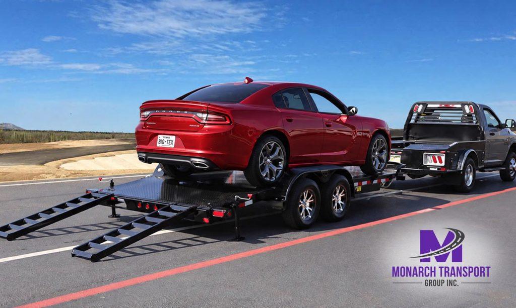 Monarch - How Car Carrier Trucks Work- Single-Car vs Multi-Car Transport Explained 4 Single-car flatbed tilt trailer carrying one modern sedan, with a compact loading deck, metal loading ramp, and visible wheel straps, parked near a residential driveway.