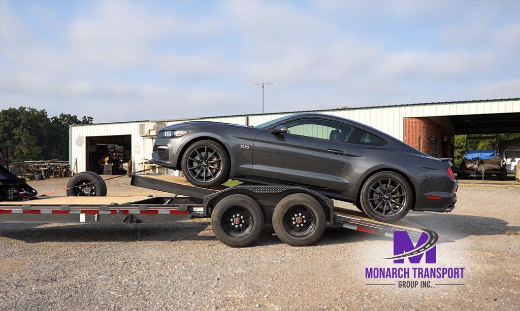 Monarch - How Car Carrier Trucks Work- Single-Car vs Multi-Car Transport Explained 7 Inoperable sedan being winched onto a specialized flatbed car carrier, with the winch cable attached to the front towing point, aligned loading ramps, and the vehicle carefully pulled onto the trailer.